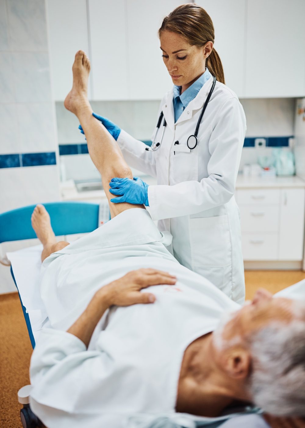 Female doctor examining senior patient's leg at orthopedic clinic.