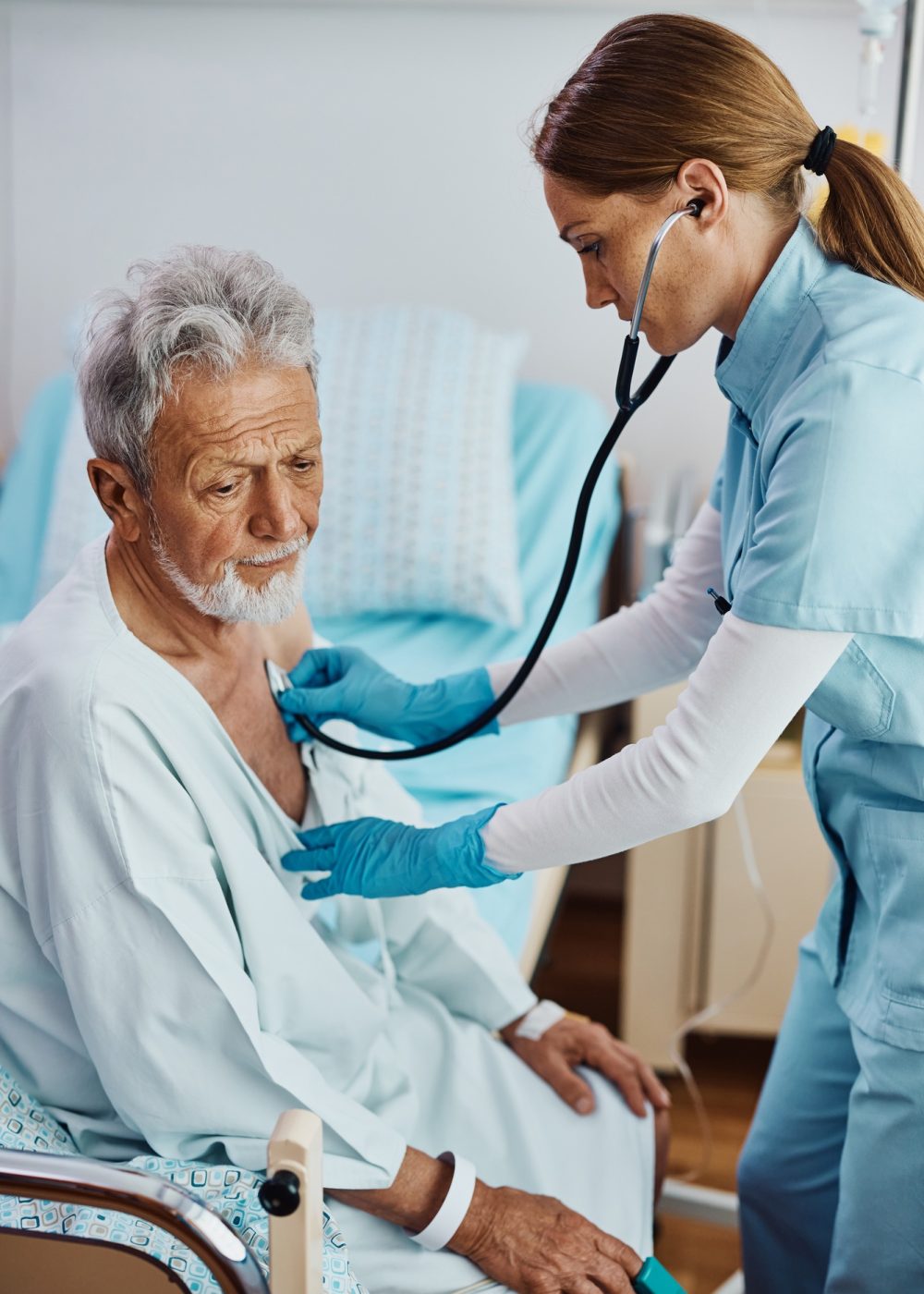 Nurse listening heartbeat of recovering senior patient in the hospital ward.